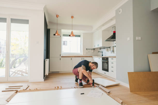 Man kneeling on kitchen floor assembling cabinets