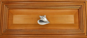 Left flange Conch shell knob on wood cabinet drawer - full view